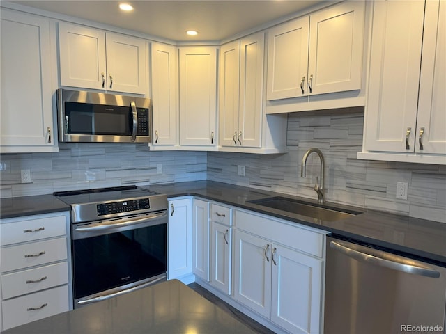 kitchen featuring appliances with stainless steel finishes, decorative backsplash, white cabinets, and sink