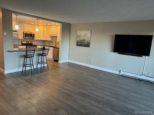 living room with dark hardwood / wood-style floors, sink, a baseboard heating unit, and a textured ceiling