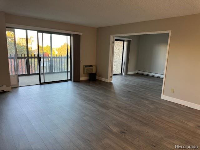 unfurnished room featuring a wall mounted air conditioner, dark hardwood / wood-style floors, baseboard heating, and a textured ceiling