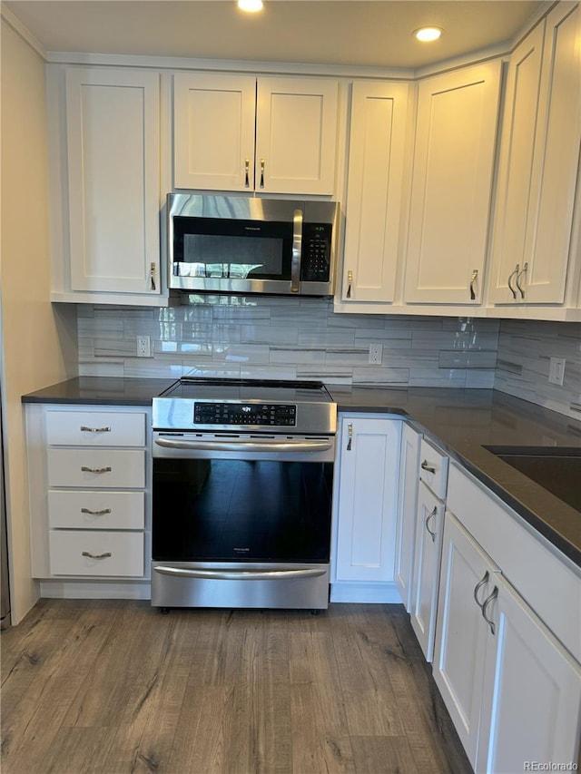 kitchen with appliances with stainless steel finishes, white cabinetry, tasteful backsplash, and recessed lighting