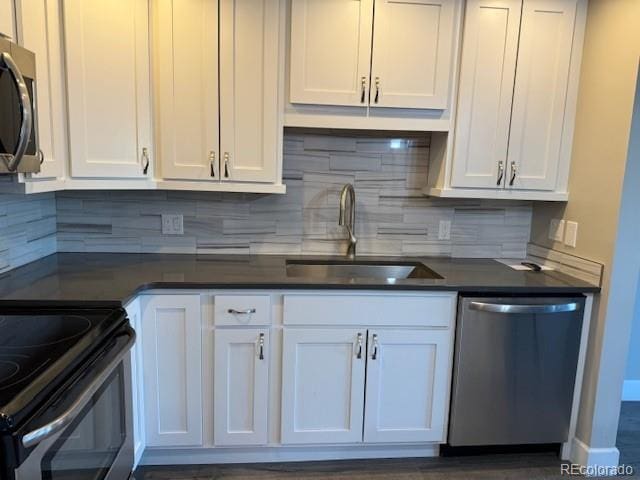 kitchen featuring stainless steel appliances, a sink, white cabinetry, dark countertops, and decorative backsplash