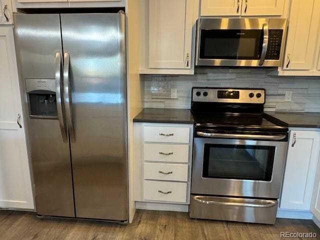 kitchen with stainless steel appliances, dark countertops, dark wood finished floors, and white cabinets