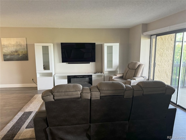 living area featuring wood finished floors, baseboards, and a textured ceiling
