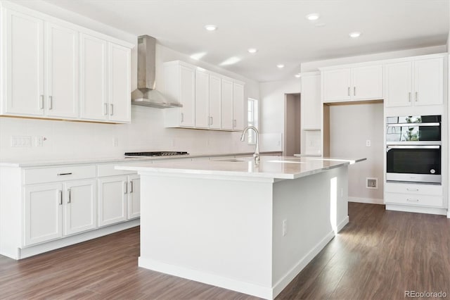 13765 Emerald Lake St, Parker, CO 80138 - kitchen featuring wall chimney exhaust hood, a sink, dark wood-style flooring, a center island with sink, and recessed lighting