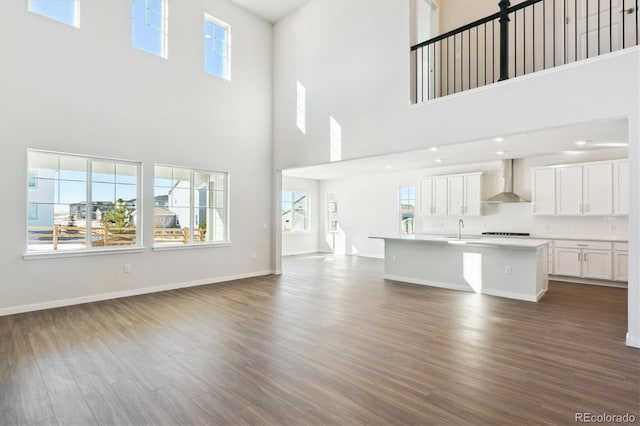 13765 Emerald Lake St, Parker, CO 80138 - unfurnished living room featuring a towering ceiling, dark wood finished floors, a sink, plenty of natural light, and baseboards