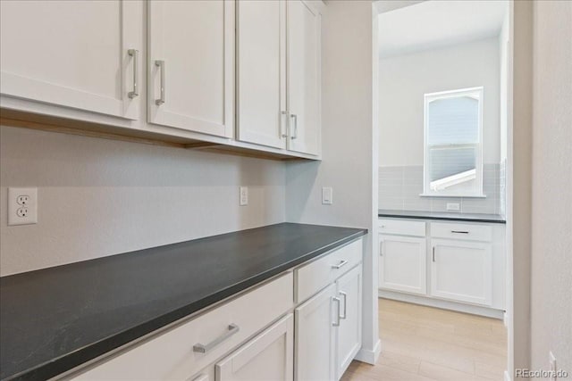 13765 Emerald Lake St, Parker, CO 80138 - kitchen featuring dark countertops, tasteful backsplash, white cabinets, and light wood-style flooring