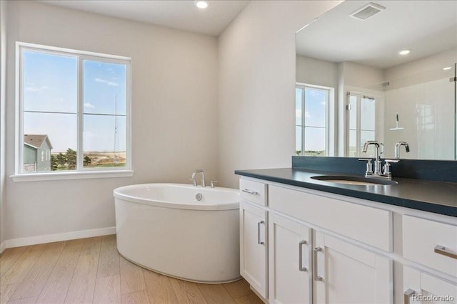 13765 Emerald Lake St, Parker, CO 80138 - full bath with healthy amount of natural light, vanity, a freestanding bath, wood finished floors, and recessed lighting