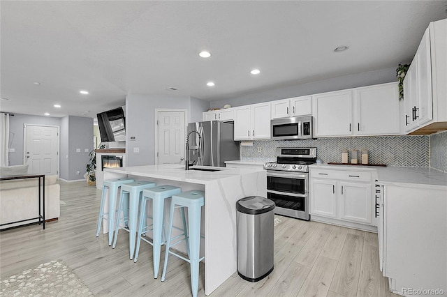 5813 Ceylon St, Denver, CO 80249 - kitchen with stainless steel appliances, light wood-style floors, tasteful backsplash, recessed lighting, and white cabinets