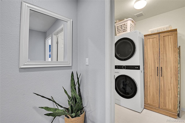5813 Ceylon St, Denver, CO 80249 - laundry room with stacked washer / drying machine, a textured wall, and light flooring