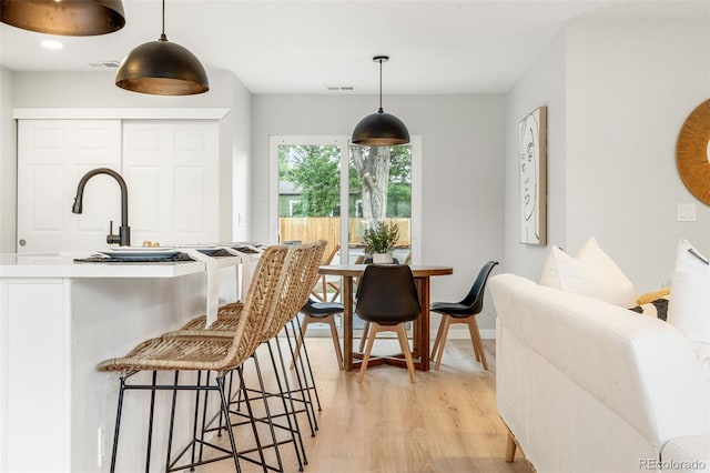 3061 S Glencoe St, Denver, CO 80222 - kitchen with light wood-type flooring, a kitchen bar, and pendant lighting