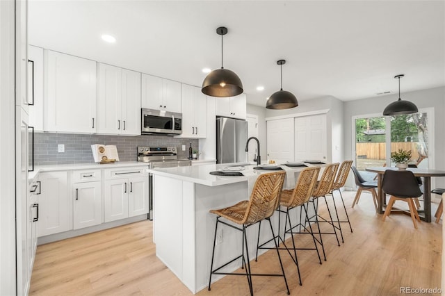 3061 S Glencoe St, Denver, CO 80222 - kitchen featuring appliances with stainless steel finishes, light wood-style flooring, light countertops, decorative backsplash, and recessed lighting
