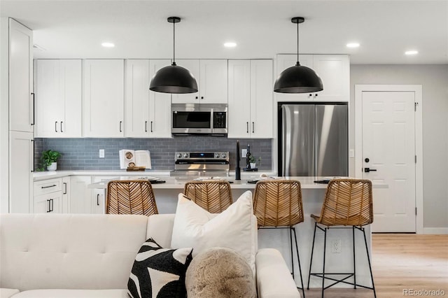 3061 S Glencoe St, Denver, CO 80222 - kitchen with appliances with stainless steel finishes, light countertops, backsplash, light wood-style flooring, and recessed lighting