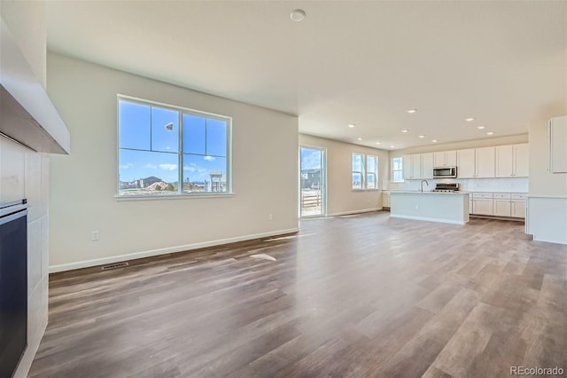 unfurnished living room featuring sink and light hardwood / wood-style flooring