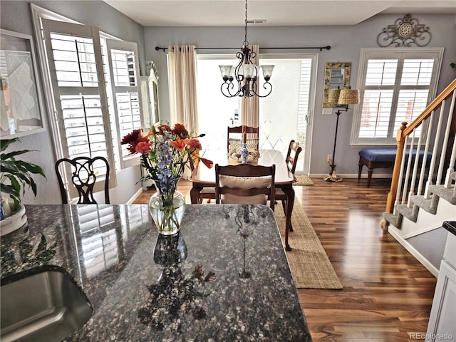 dining room with dark wood-type flooring, a notable chandelier, and a healthy amount of sunlight