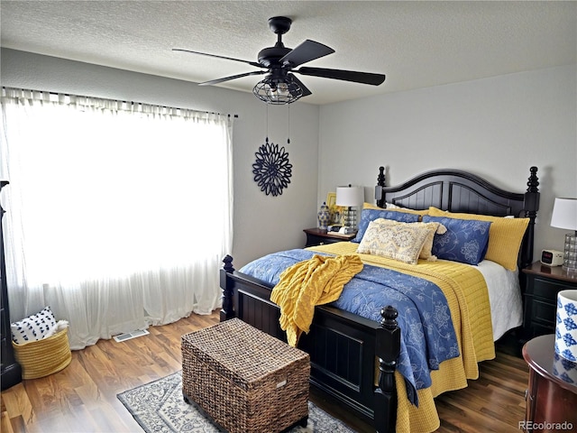 bedroom with ceiling fan, a textured ceiling, and hardwood / wood-style flooring