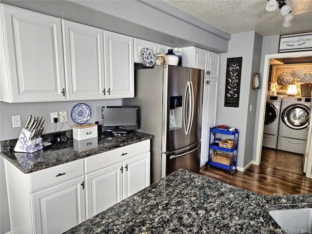 kitchen with dark stone countertops, washing machine and clothes dryer, stainless steel fridge with ice dispenser, a textured ceiling, and white cabinets