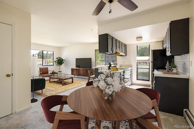 dining room with light colored carpet, a baseboard heating unit, and ceiling fan