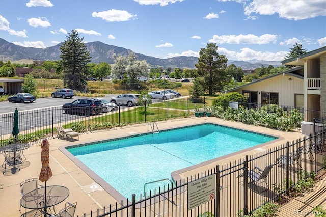 view of swimming pool featuring a patio area, a fenced in pool, a mountain view, and fence