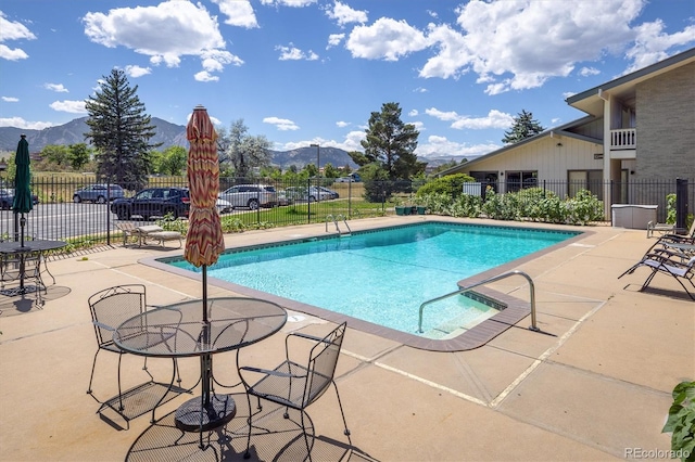 view of pool featuring a patio area, fence, and a mountain view