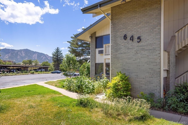 exterior space featuring a mountain view, a yard, and brick siding