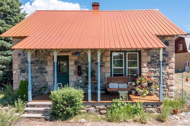 689 County Road 4, Howard, CO 81233 - view of front of property featuring stone siding, a chimney, a porch, and a metal roof