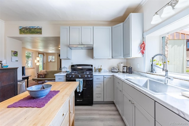 689 County Road 4, Howard, CO 81233 - kitchen with black range with gas stovetop, under cabinet range hood, butcher block counters, light wood-style flooring, and crown molding