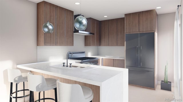 kitchen with high end fridge, range, light countertops, a kitchen breakfast bar, and recessed lighting