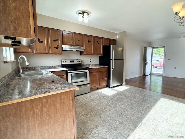 4312 S Xenon St, Morrison, CO 80465 - kitchen featuring appliances with stainless steel finishes, a sink, under cabinet range hood, baseboards, and a chandelier