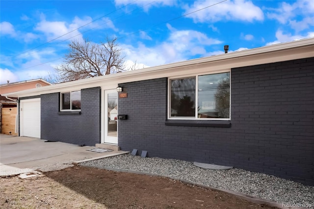 9101 Clarkson St, Thornton, CO 80229 - view of exterior entry with an attached garage, brick siding, and driveway