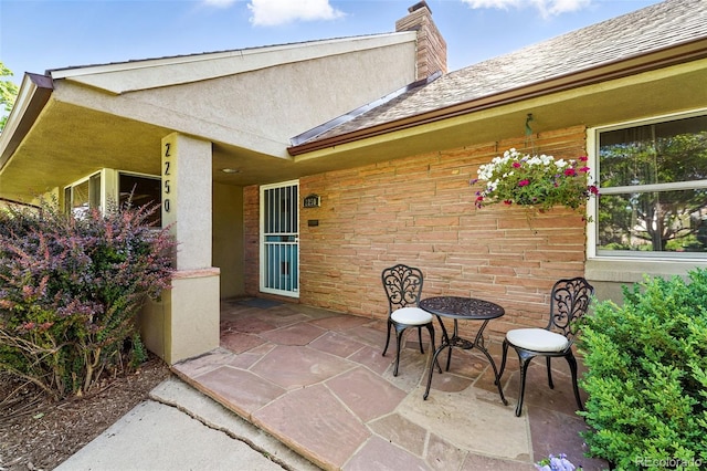 2250 N Monaco Pkwy, Denver, CO 80207 - view of exterior entry featuring a chimney, a patio, brick siding, and stucco siding