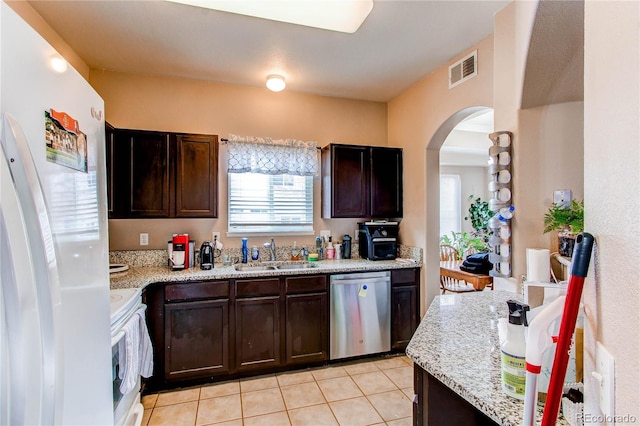 kitchen with arched walkways, dark brown cabinetry, white appliances, a sink, and visible vents