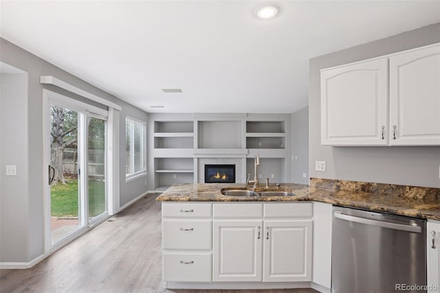 kitchen featuring white cabinets, dishwasher, dark stone countertops, and a sink