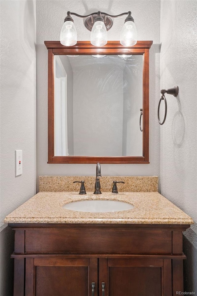bathroom featuring a textured wall and vanity