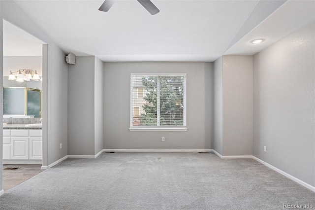 spare room featuring baseboards, visible vents, a ceiling fan, and light colored carpet