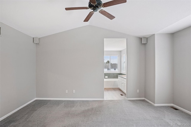 interior space featuring vaulted ceiling, ceiling fan, light colored carpet, baseboards, and visible vents