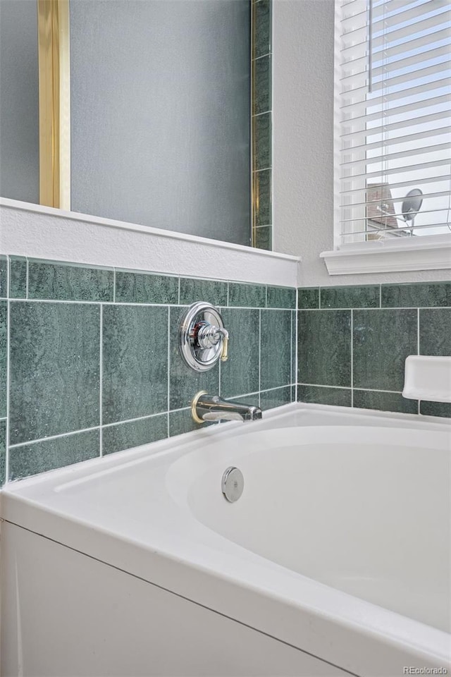 bathroom featuring a bath and a textured wall