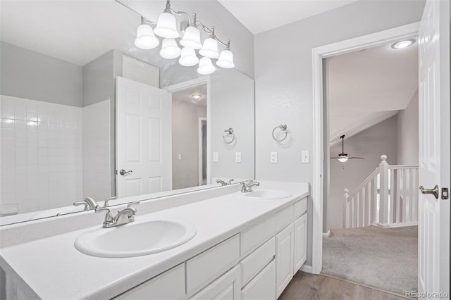 bathroom with double vanity, wood finished floors, ceiling fan with notable chandelier, and a sink
