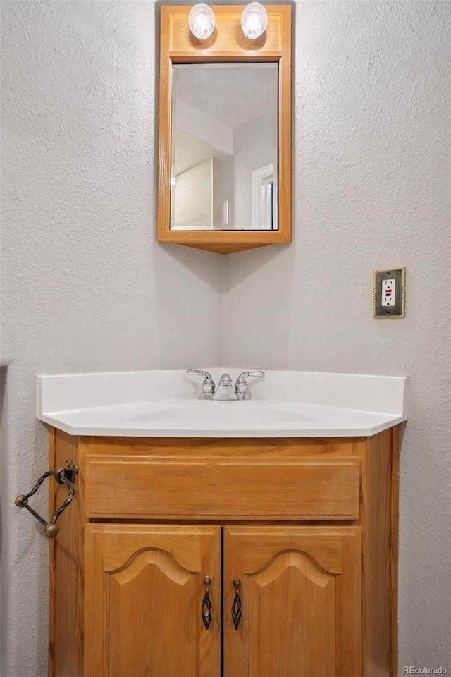 bathroom with a textured wall and vanity