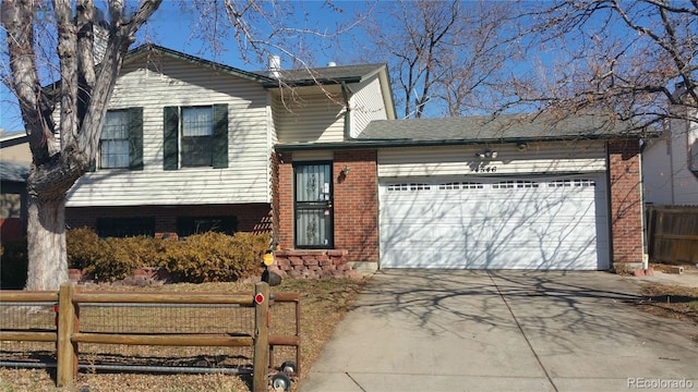 tri-level home featuring fence, concrete driveway, brick siding, and an attached garage