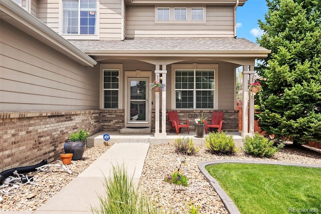 12942 Leyden St, Thornton, CO 80602 - view of exterior entry featuring a porch, brick siding, and a shingled roof