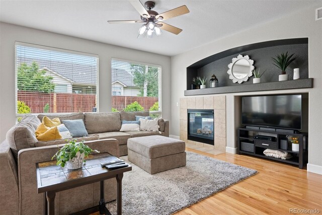 12942 Leyden St, Thornton, CO 80602 - living room featuring wood finished floors, a tiled fireplace, and a ceiling fan