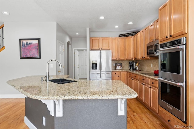 12942 Leyden St, Thornton, CO 80602 - kitchen with appliances with stainless steel finishes, a sink, light wood finished floors, recessed lighting, and backsplash