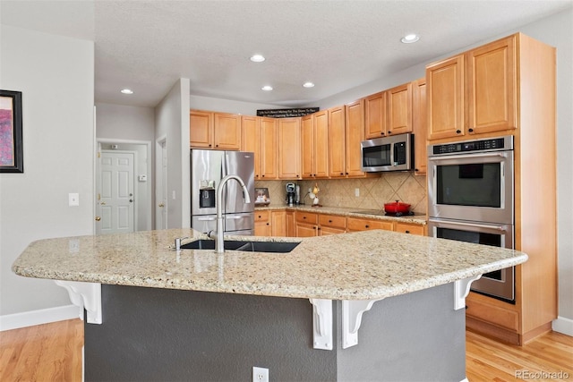 12942 Leyden St, Thornton, CO 80602 - kitchen featuring appliances with stainless steel finishes, a kitchen breakfast bar, light wood-type flooring, baseboards, and recessed lighting