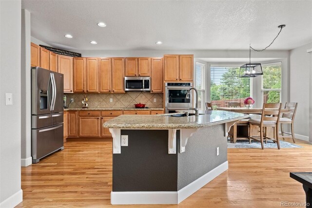 12942 Leyden St, Thornton, CO 80602 - kitchen with appliances with stainless steel finishes, baseboards, light wood-type flooring, tasteful backsplash, and recessed lighting