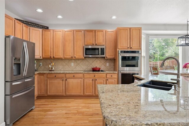 12942 Leyden St, Thornton, CO 80602 - kitchen with appliances with stainless steel finishes, a sink, light wood finished floors, recessed lighting, and light stone countertops