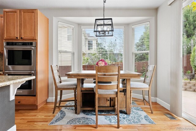 12942 Leyden St, Thornton, CO 80602 - dining room with baseboards, light wood-type flooring, and a chandelier