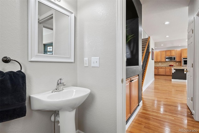 12942 Leyden St, Thornton, CO 80602 - bathroom with wood finished floors, decorative backsplash, a textured wall, and recessed lighting
