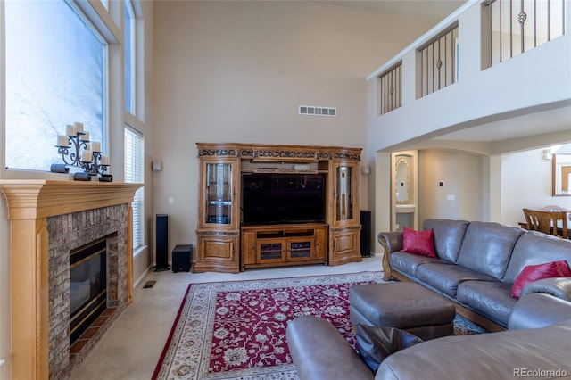 carpeted living room featuring a fireplace and a towering ceiling