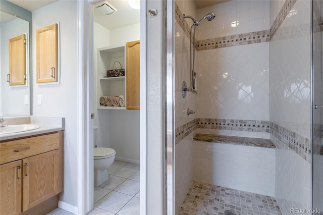 bathroom with vanity, toilet, tile patterned flooring, and tiled shower