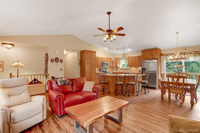 living room with lofted ceiling, rail lighting, ceiling fan with notable chandelier, and light wood-type flooring